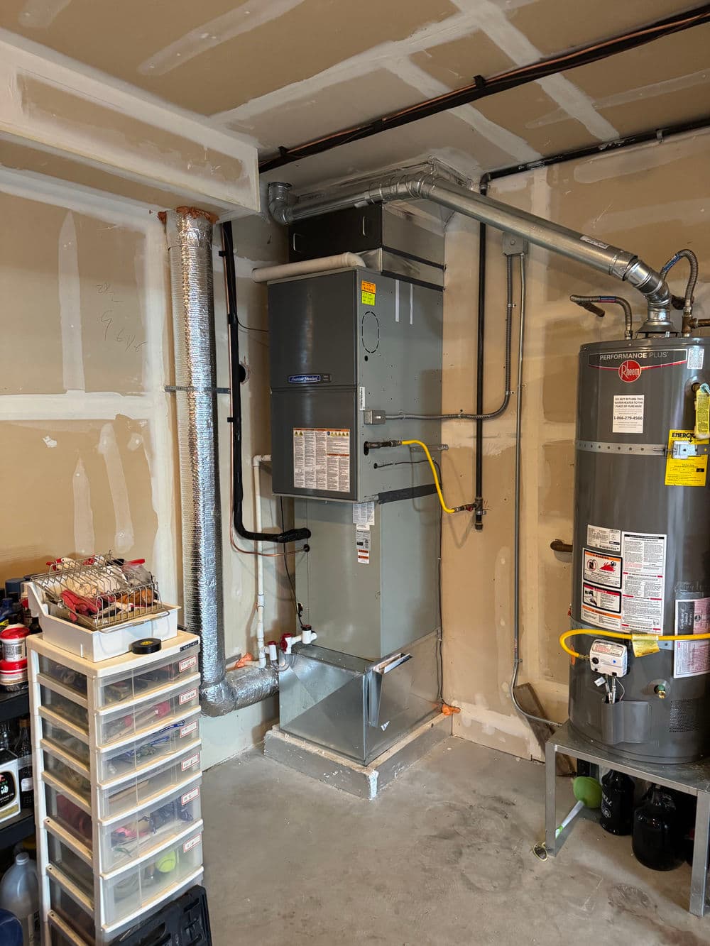 Residential garage with an HVAC system and water heater, showcasing utility organization.